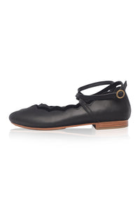 Black ballerina shoe with a strap on a white background