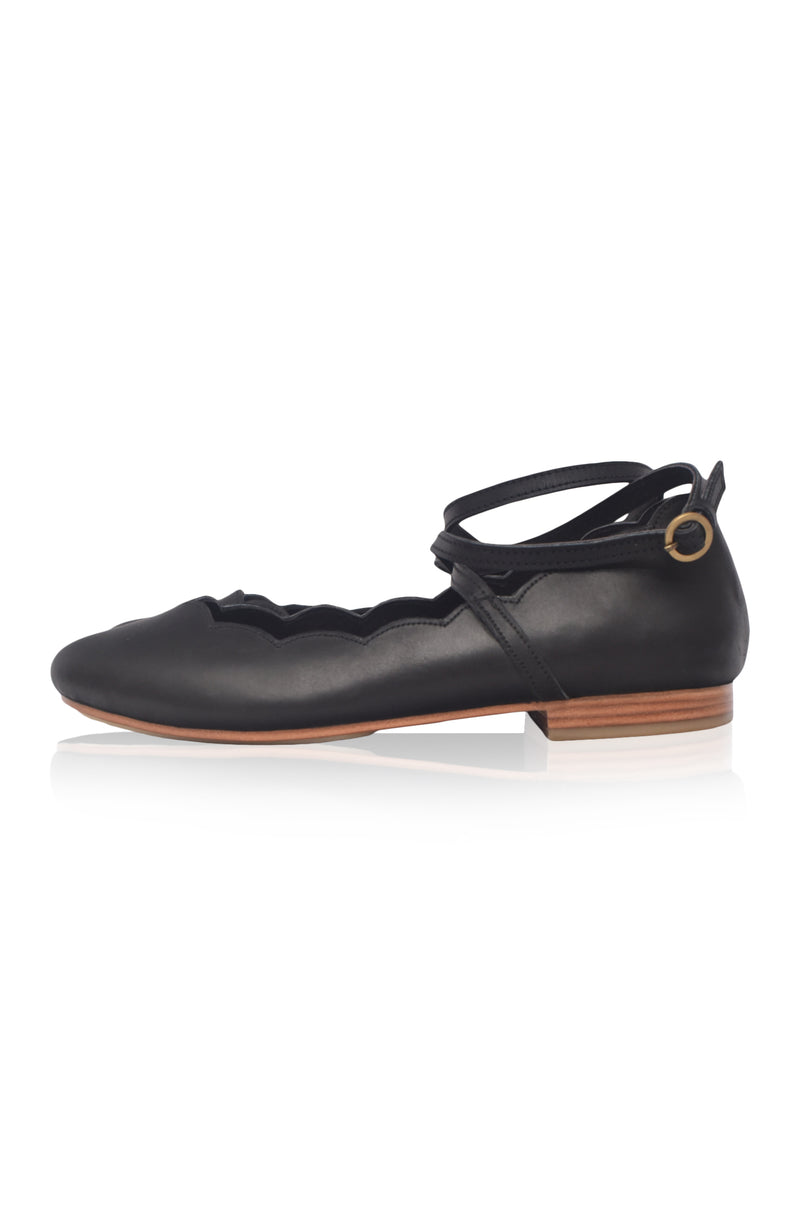Black ballerina shoe with a strap on a white background