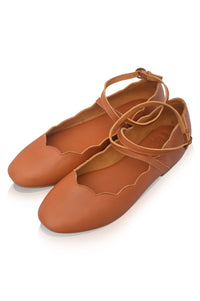 Pair of brown ballet flats with ankle straps on a white background