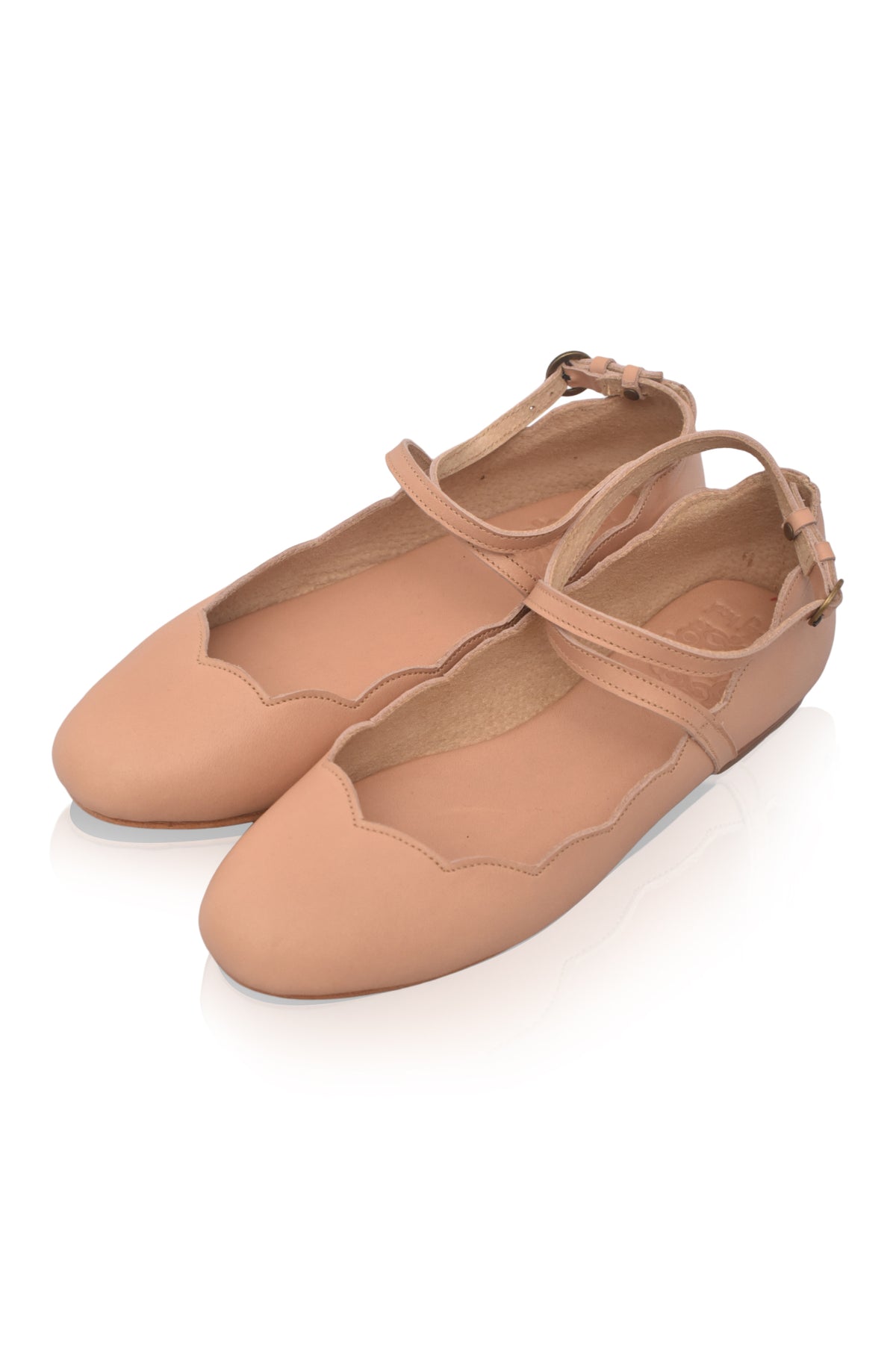Pair of beige ballet flats on a white background