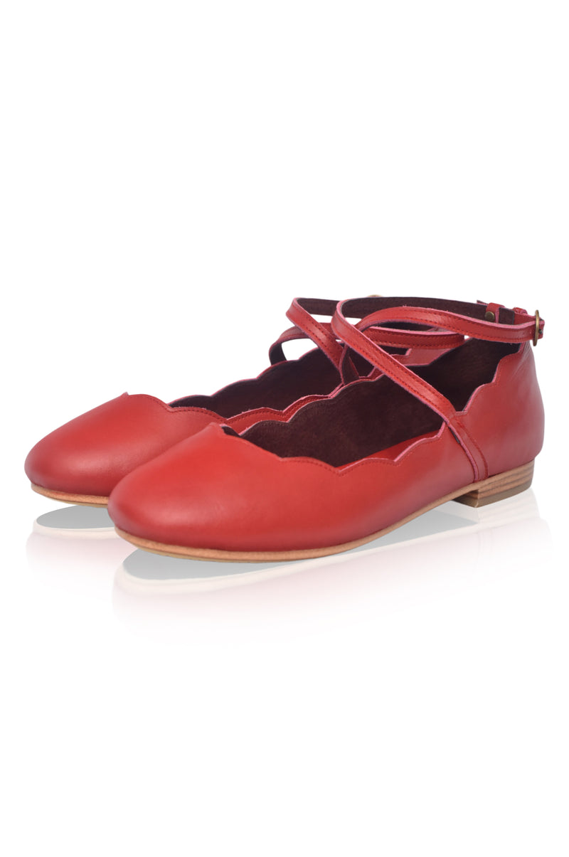 Red ballerina shoes with a strap on a white background