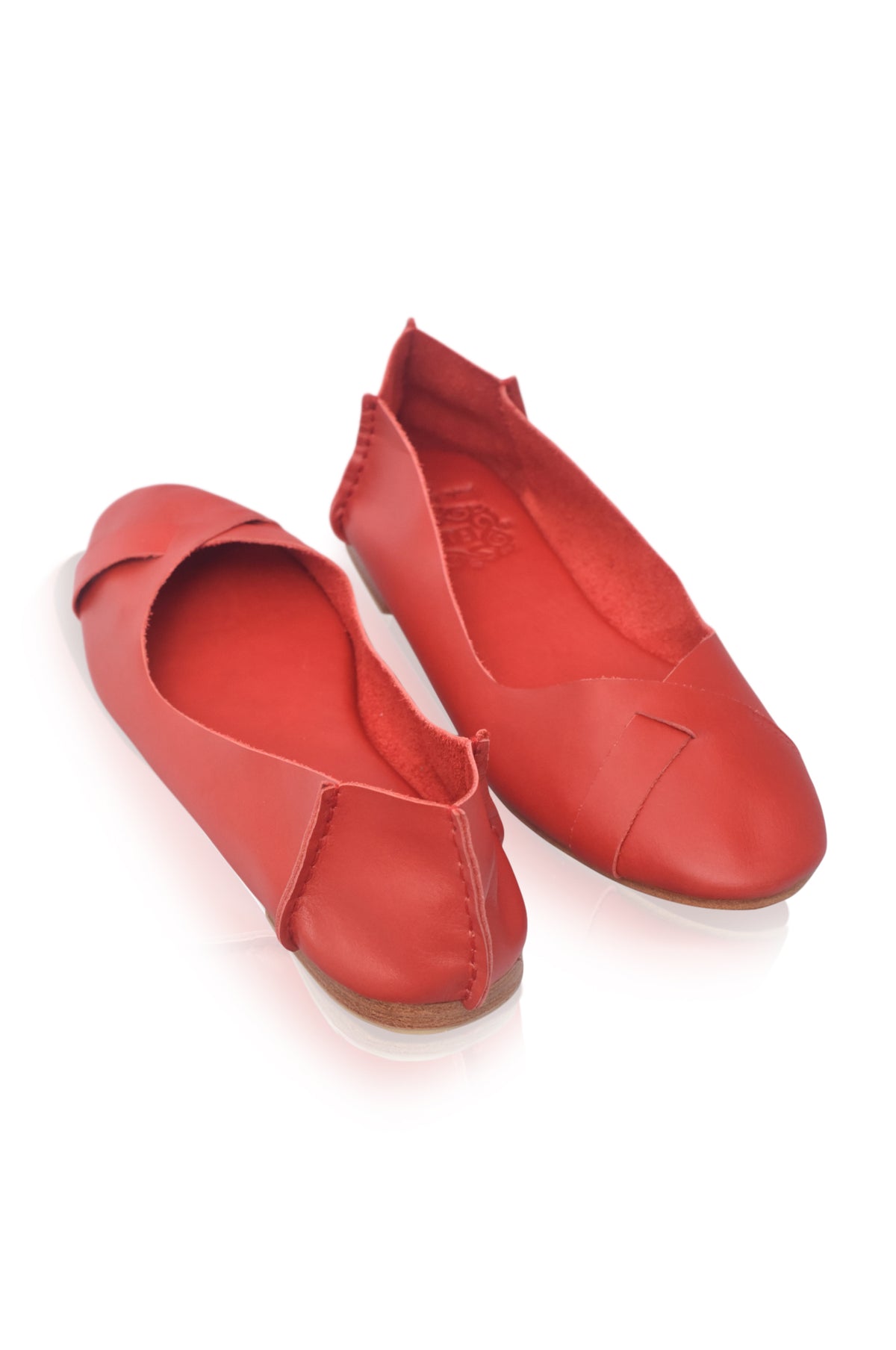 A pair of red leather ballet flats with a pointed toe and a decorative side tab, shown on a white background.