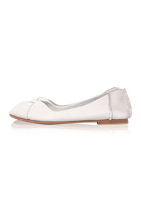 A single white leather ballet flat shoe with a pointed toe and a small decorative bow on the vamp, shown in profile against a white background with a soft reflection.
