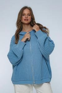 Woman wearing a blue knitted hoodie against a white background