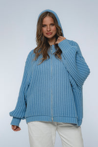 Woman wearing a blue knitted hoodie on a light gray background