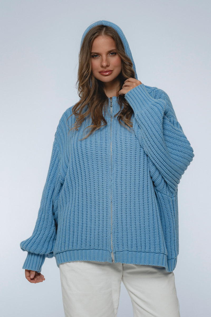 Woman wearing a blue knitted hoodie on a light gray background