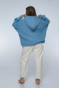 Person wearing a blue sweater with a hood on a white background