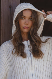 Woman wearing a white hooded jacket with a blurred background