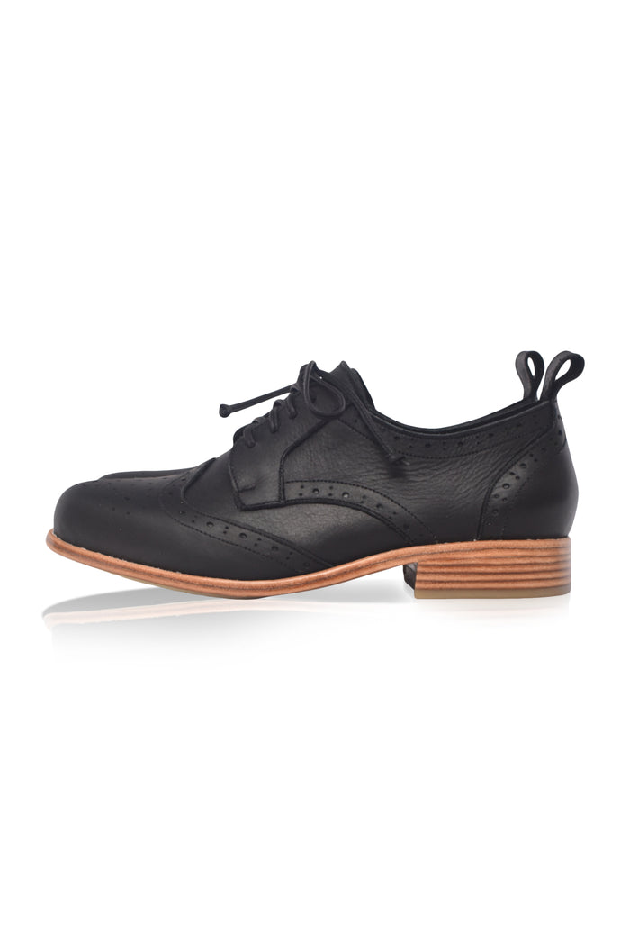 Black leather shoe with brown sole on a white background