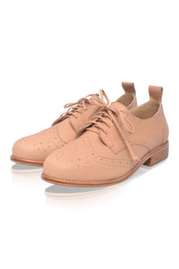Pair of beige brogue shoes on a white background