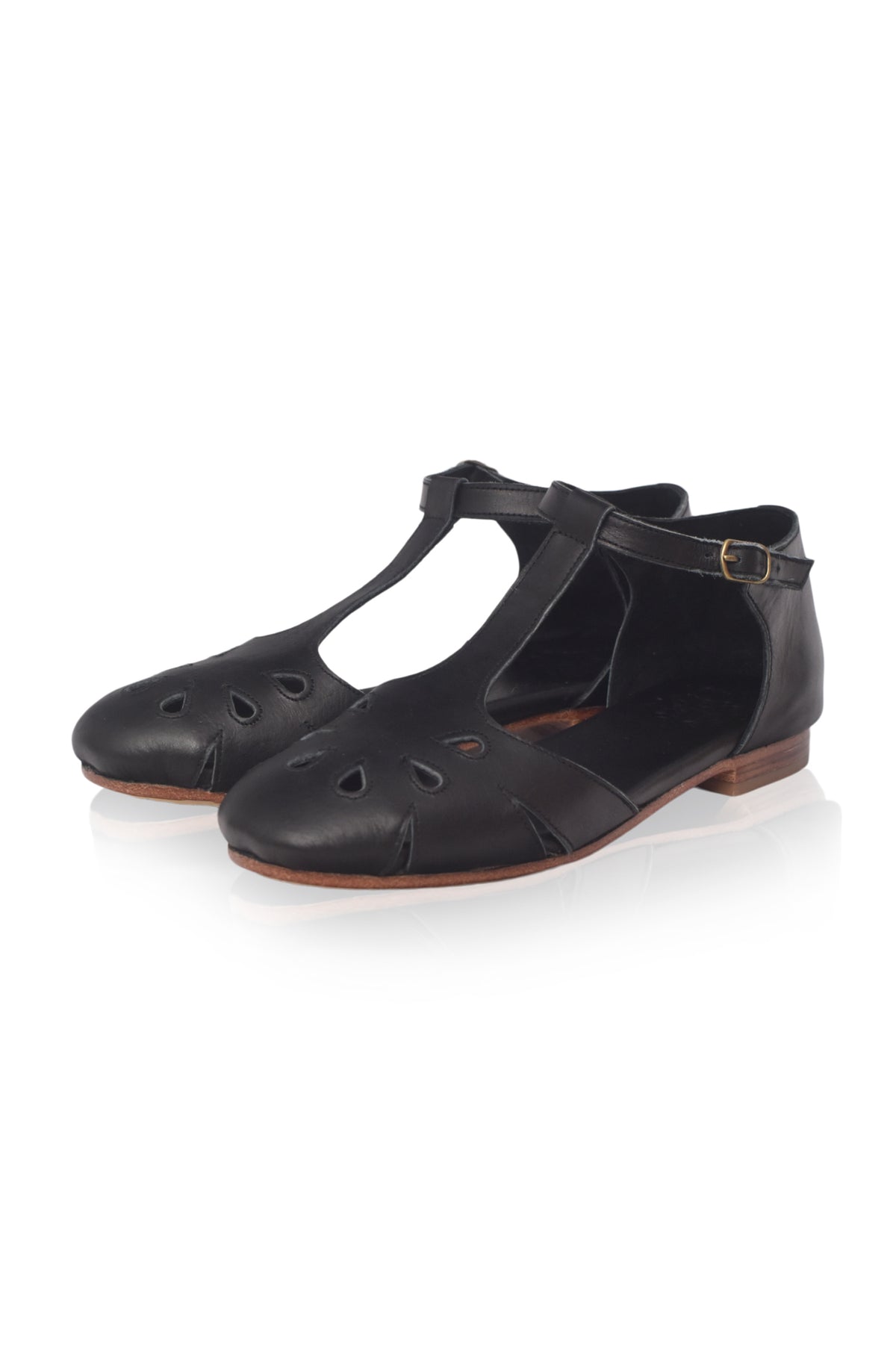 A pair of black leather T-strap flat sandals with cutout details on the toe, shown on a clean white background.