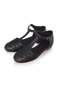 A pair of black leather T-strap Mary Jane flats with decorative cutouts on the toe, shown on a clean white background.