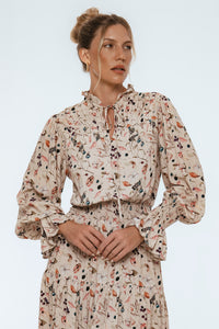 Woman wearing a floral blouse with a neutral background