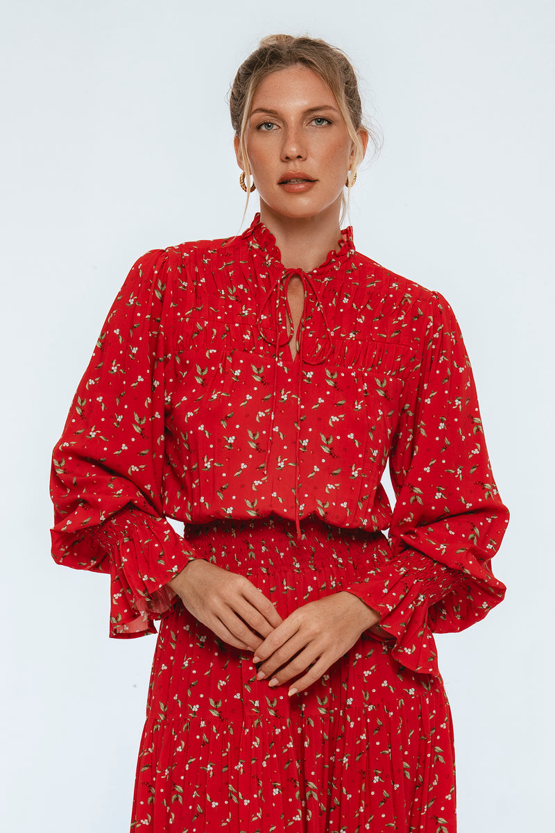 Woman wearing a red floral dress against a light gray background