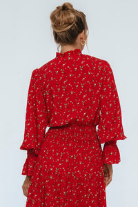 Red patterned dress worn by a person on a white background