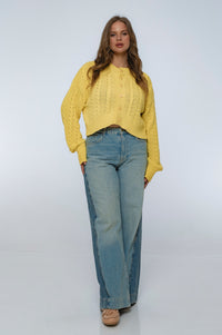 Woman wearing a yellow sweater and blue jeans on a white background