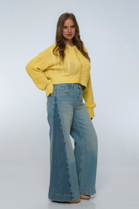 Woman wearing a yellow sweater and blue jeans on a white background