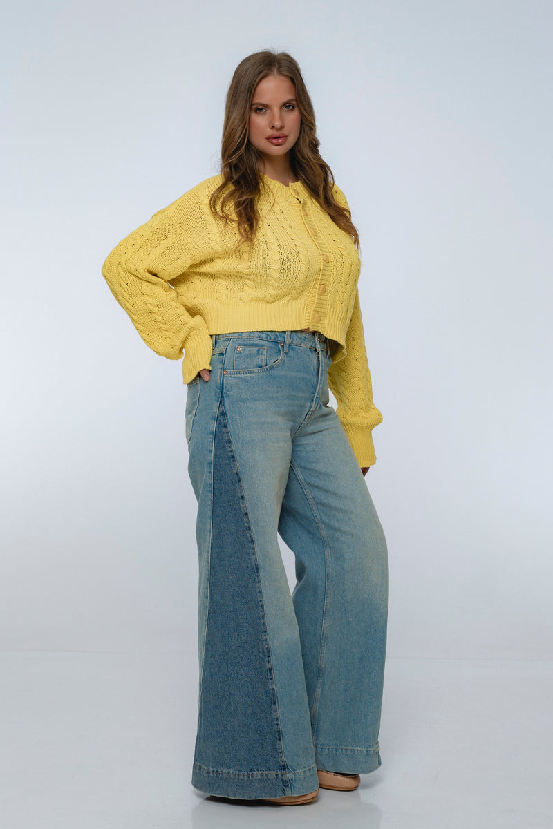 Woman wearing a yellow sweater and blue jeans on a white background