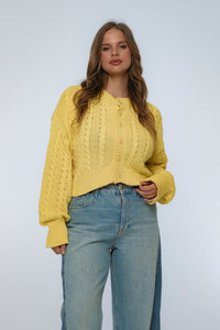 Woman wearing a yellow knitted sweater and blue jeans on a white background