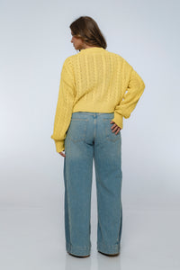 Person wearing a yellow sweater and blue jeans on a white background