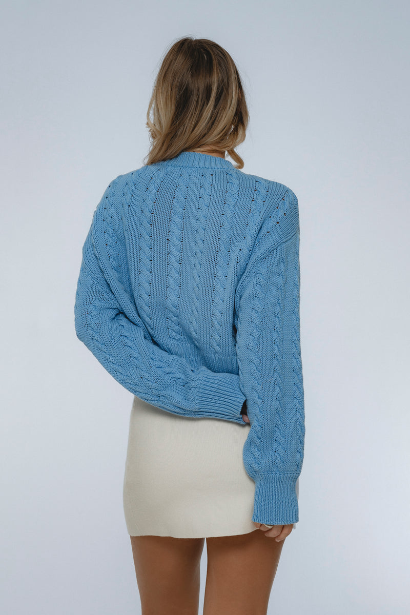 Person wearing a blue knitted sweater on a plain background