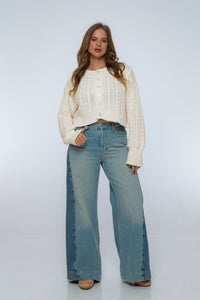 Woman wearing a white sweater and blue jeans on a white background