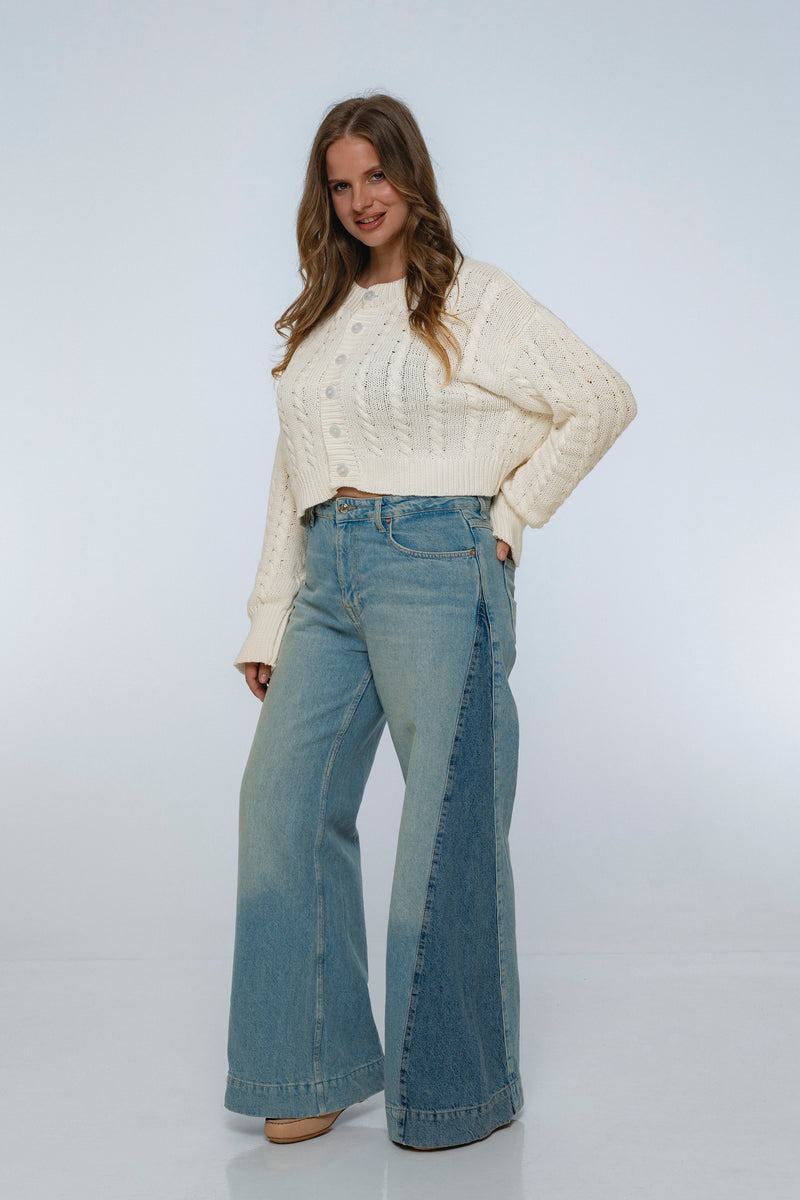 Woman wearing a cream sweater and blue jeans on a white background