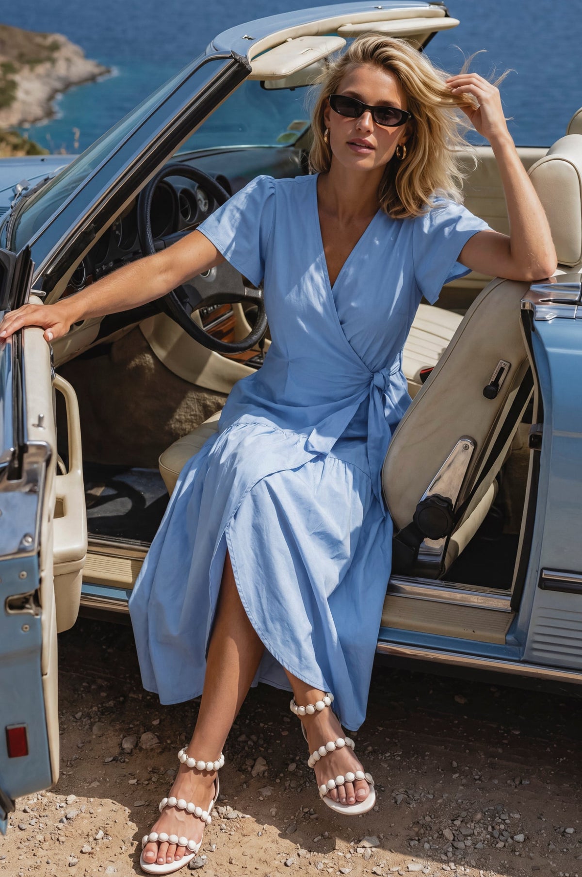 Woman in a blue dress sitting in an open car with a scenic background