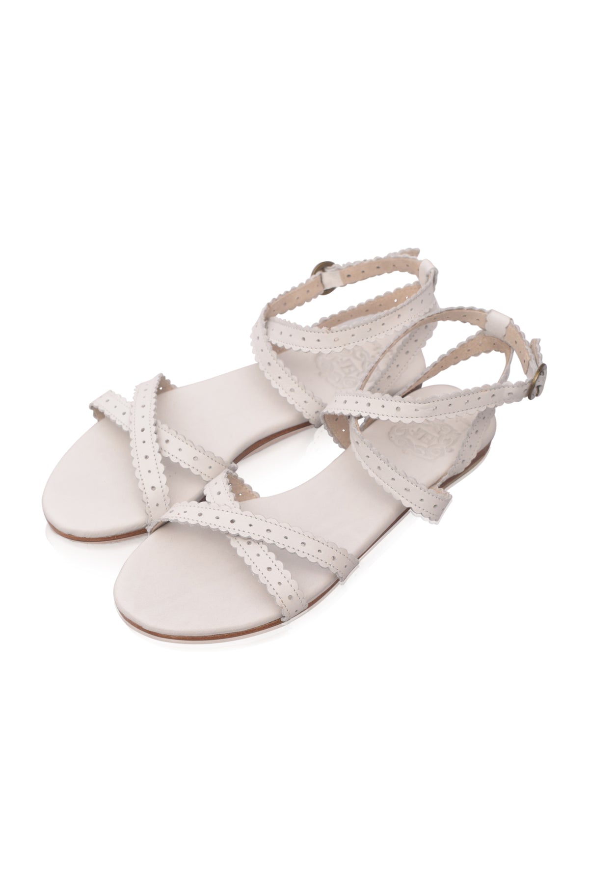 A pair of women's flat sandals in a light cream or off-white color, featuring cutout straps and adjustable ankle straps, shown on a plain white background.