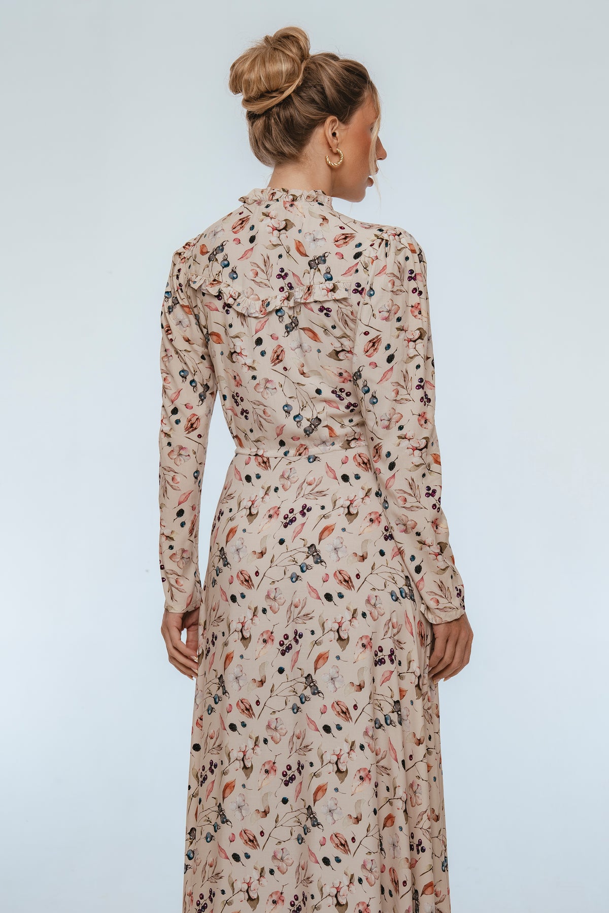 Woman wearing a floral dress against a plain background