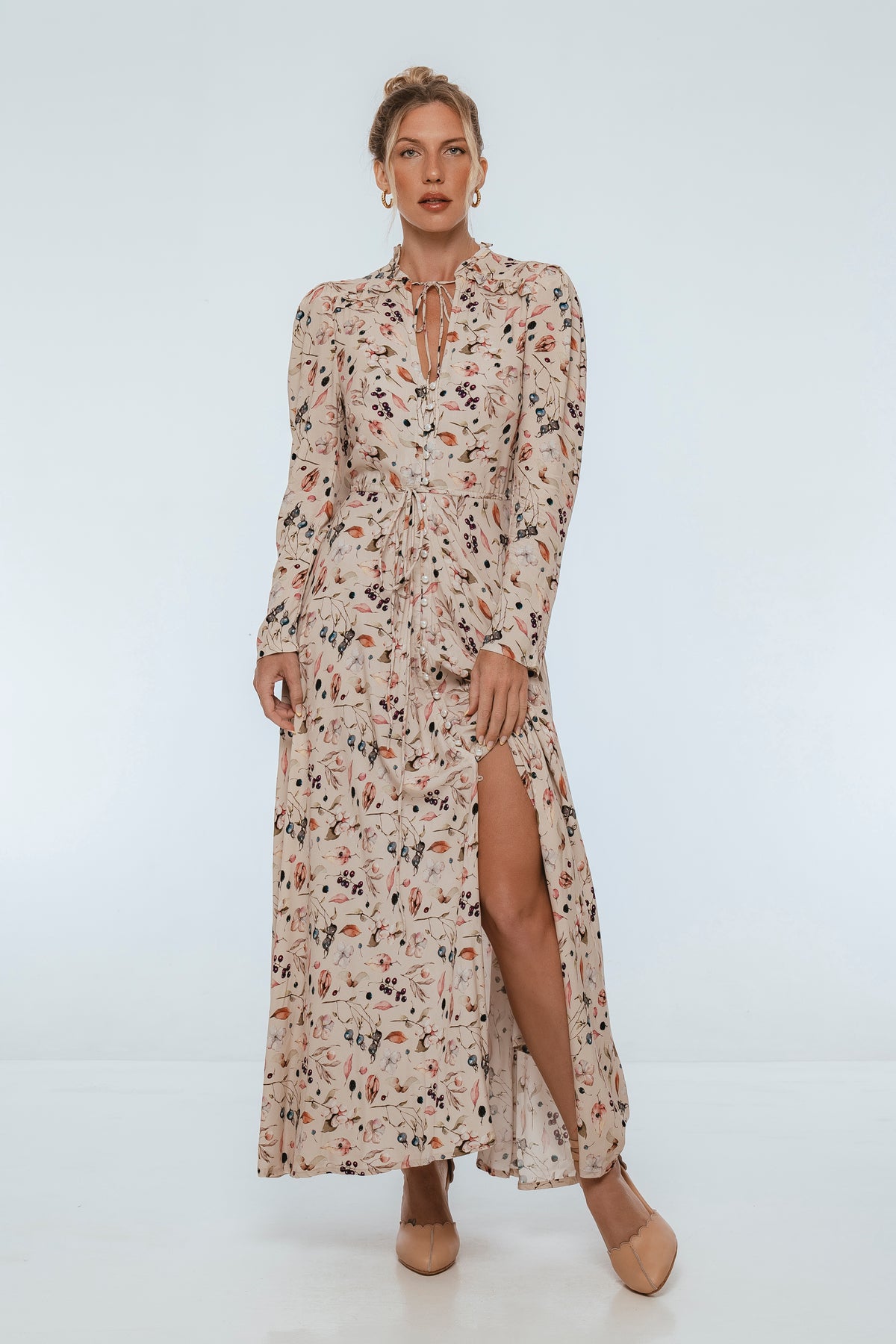 Woman wearing a floral dress with a slit on a white background