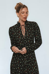 Woman wearing a black floral dress against a light gray background