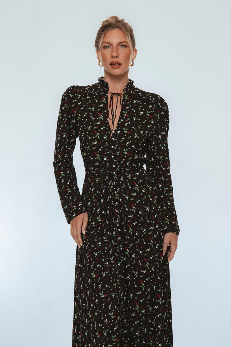 Woman wearing a black floral dress against a light gray background