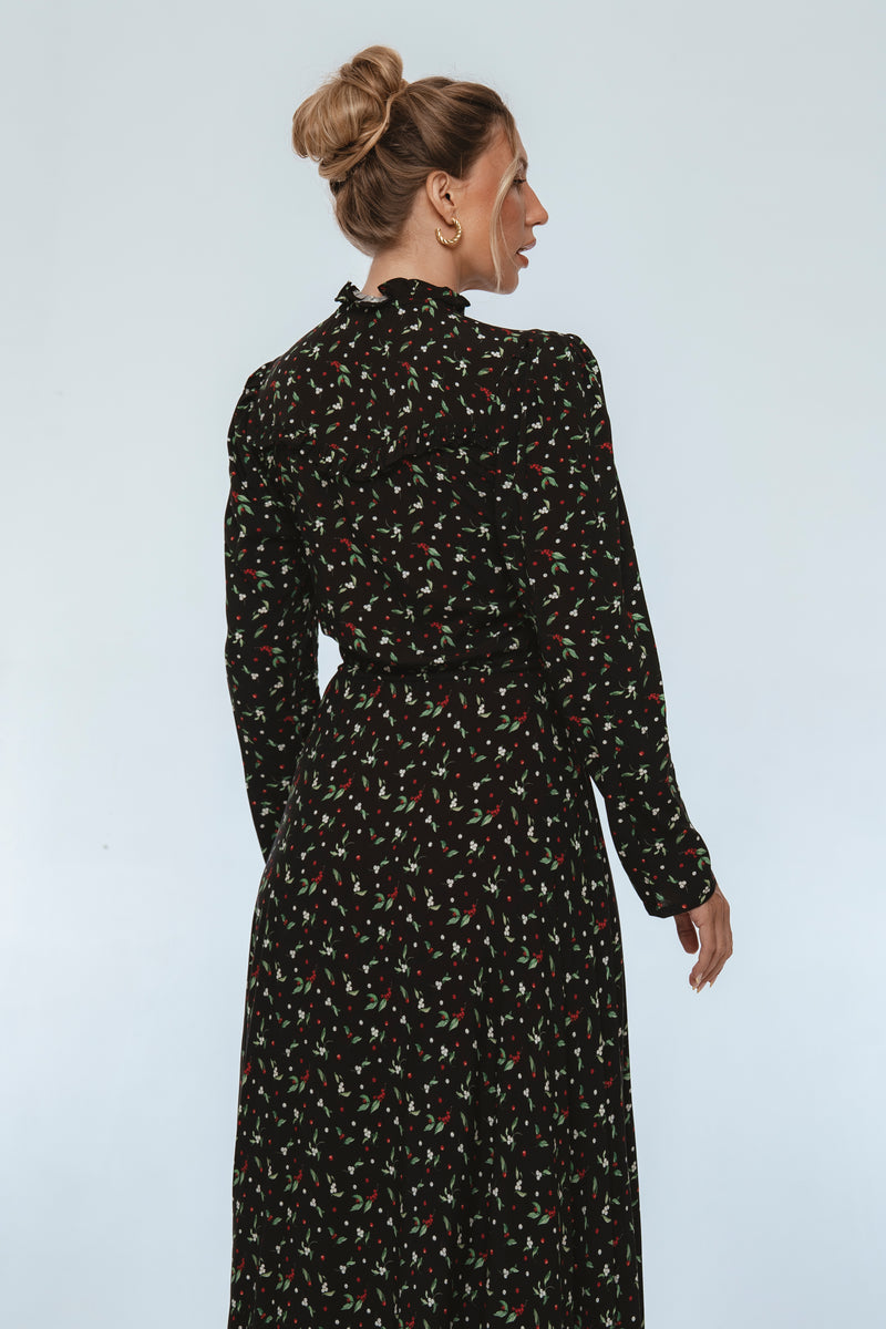 Woman wearing a black floral dress against a white background