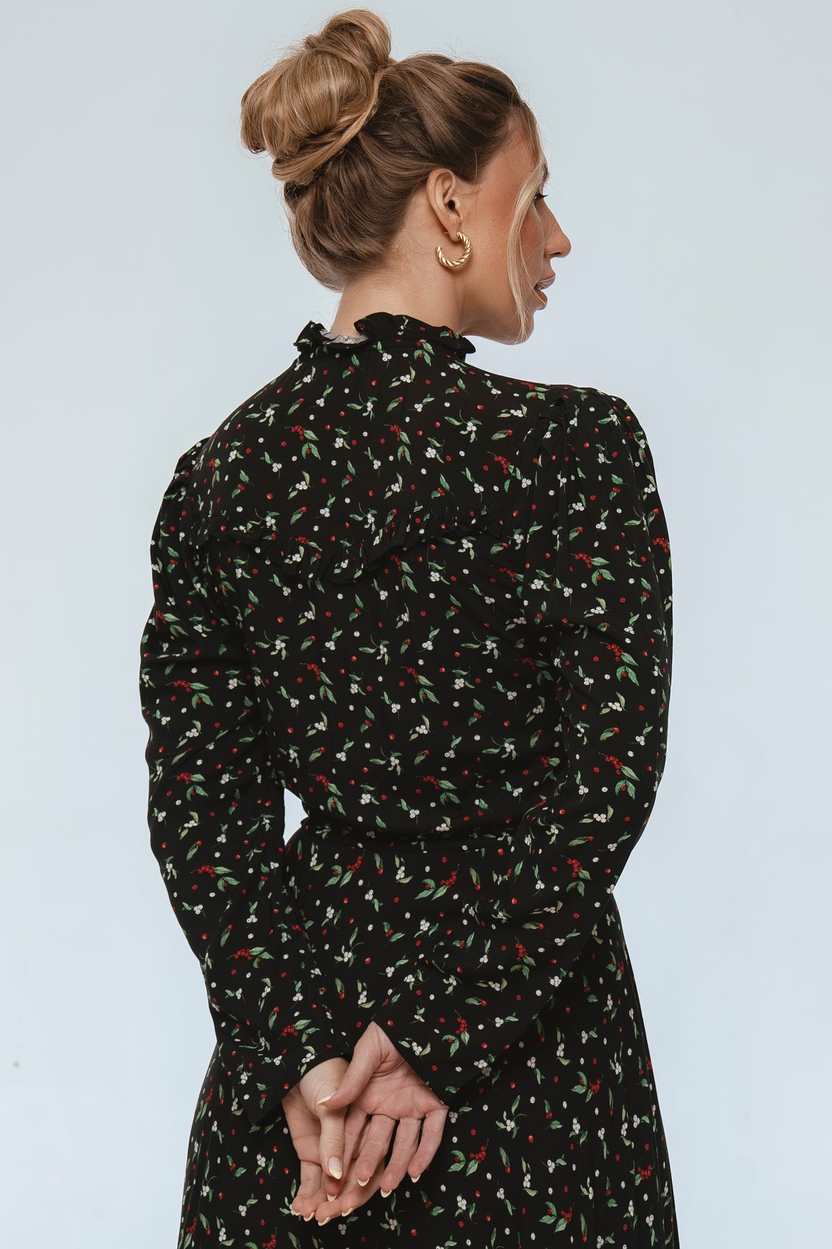 Woman wearing a black floral dress against a light gray background