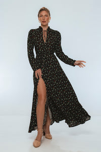 Woman wearing a black floral dress with a high slit on a white background