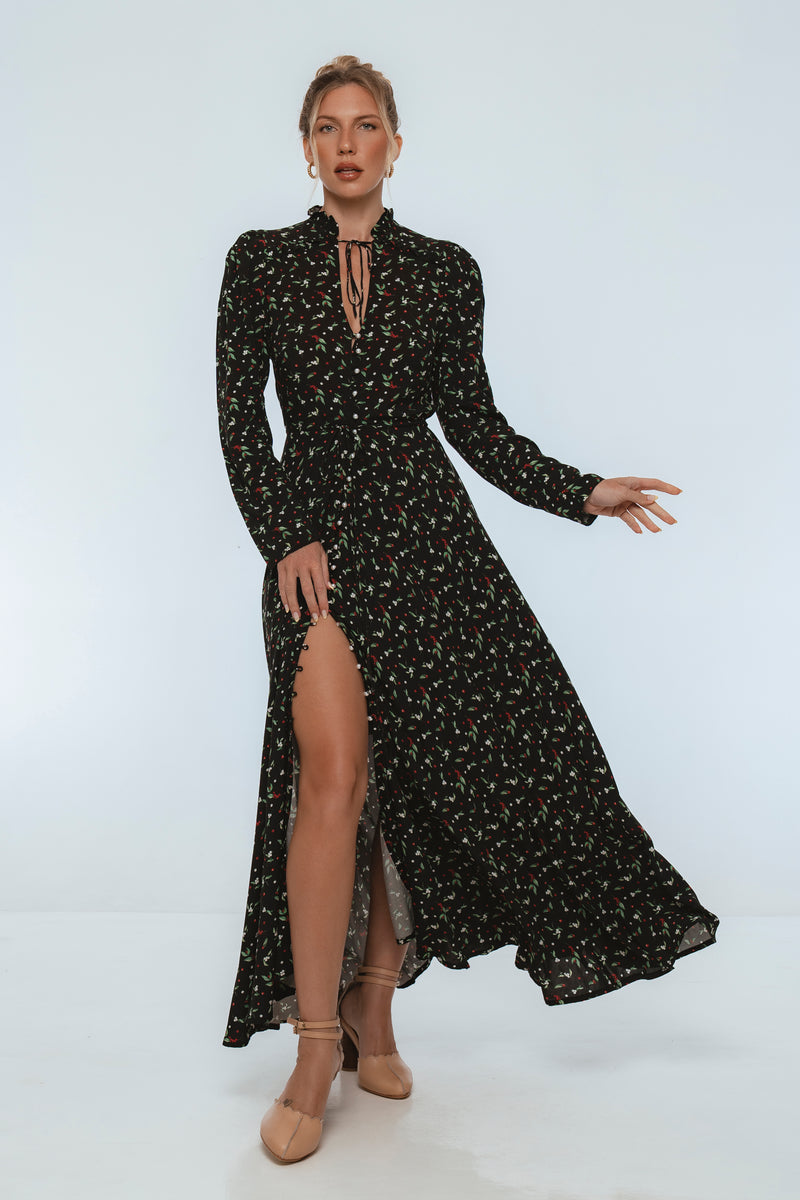 Woman wearing a black floral dress with a high slit on a white background