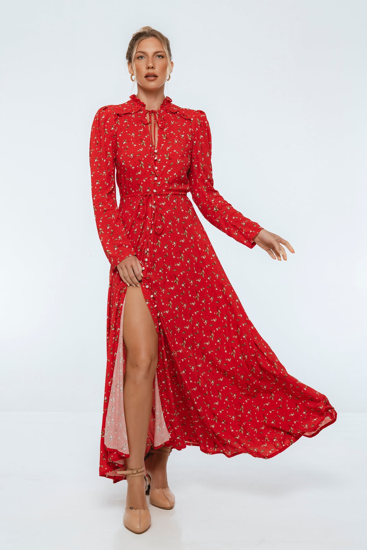 Woman wearing a red dress with a slit on a white background
