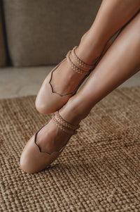 Beige ballet flats worn on a textured brown surface