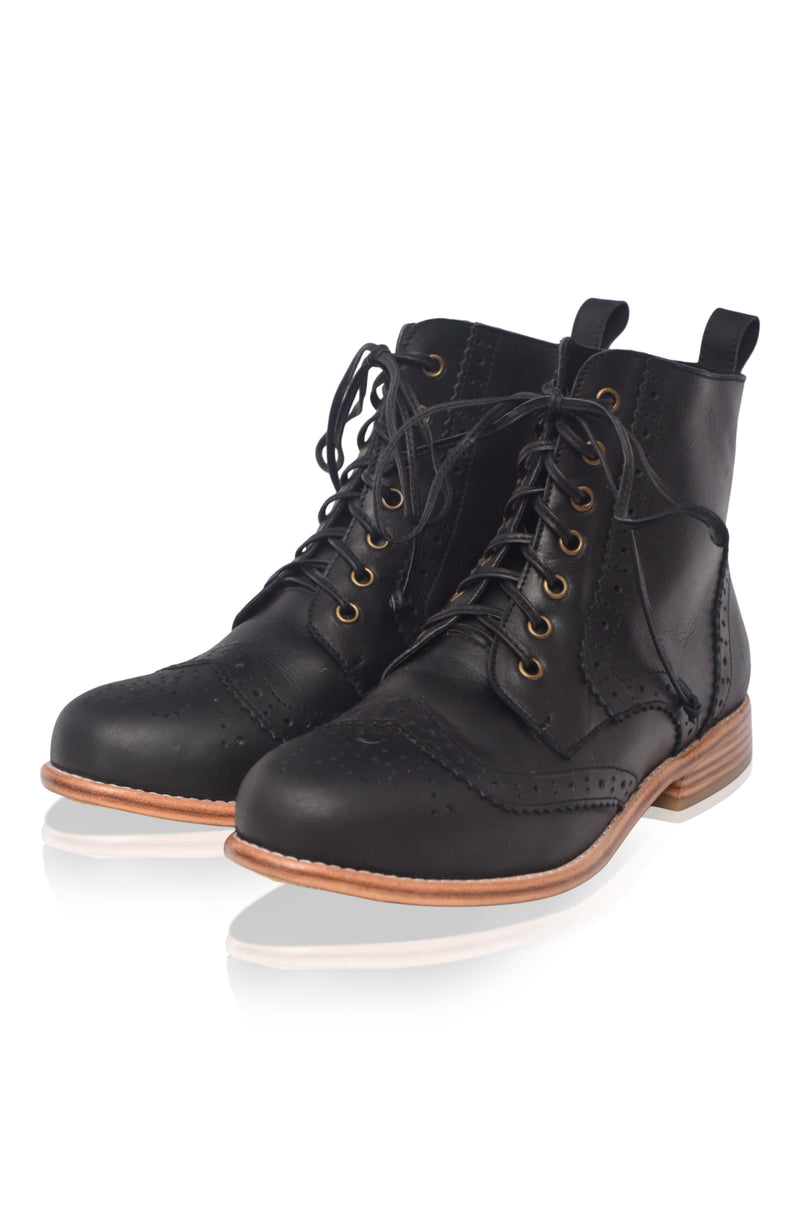 Pair of black leather boots with brown soles on a white background