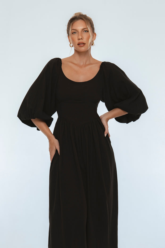 Woman wearing a black dress with puffed sleeves against a white background