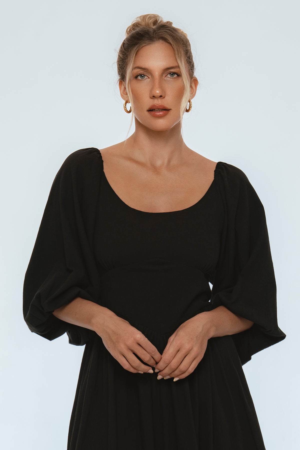 Woman wearing a black dress against a plain background