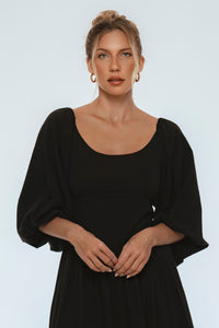 Woman wearing a black dress against a plain background