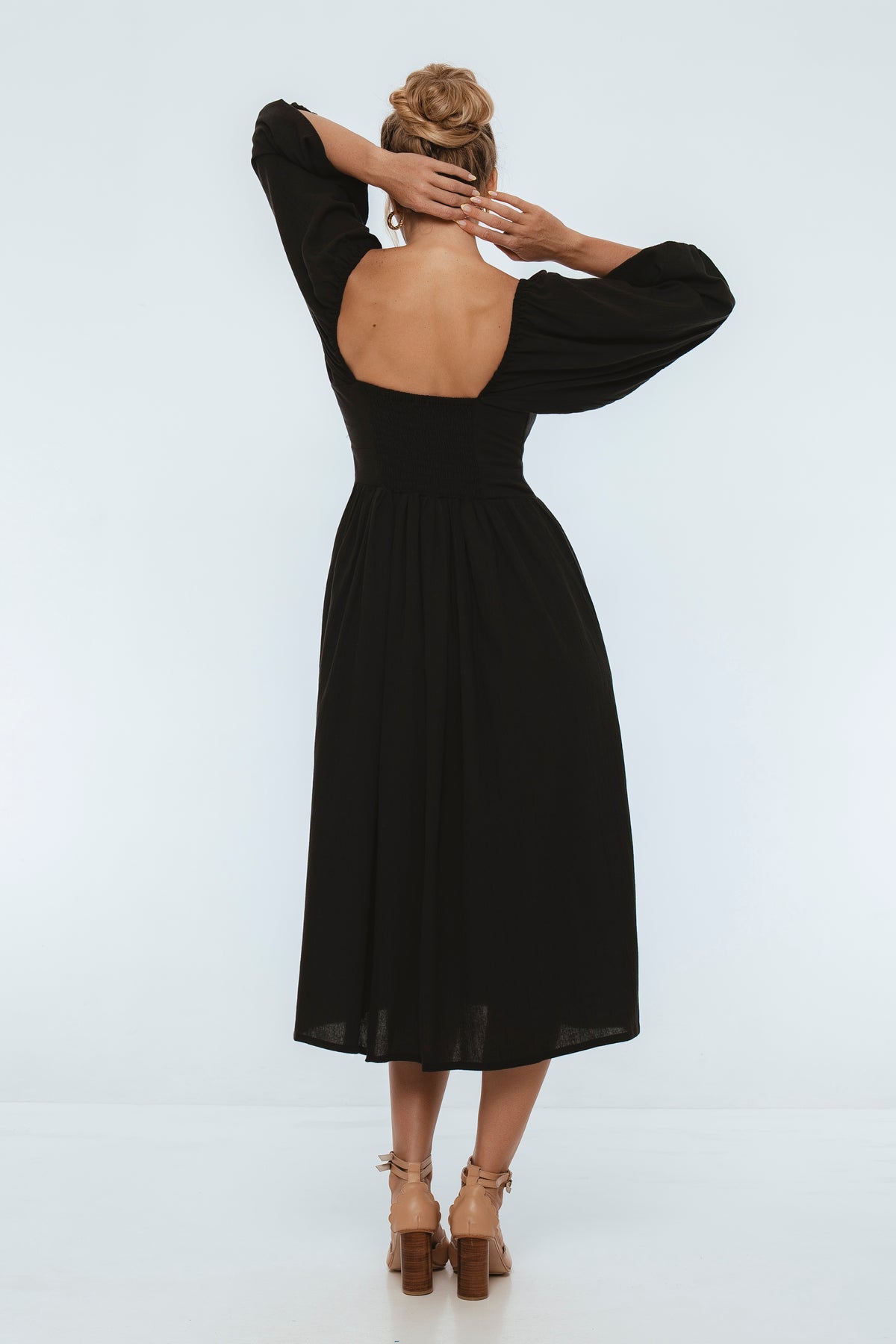 Black dress with open back worn by a person on a white background