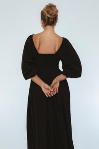 Person wearing a black dress with long sleeves on a white background