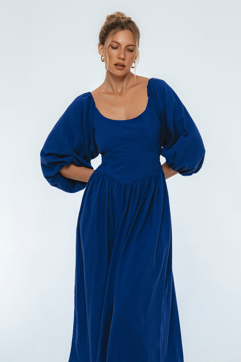 Woman wearing a blue dress with long sleeves on a white background