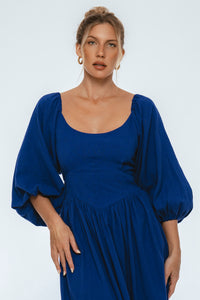 Woman wearing a blue dress with puffed sleeves on a white background