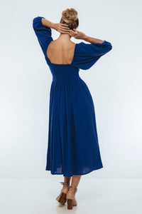 Woman wearing a blue dress with a backless design on a white background