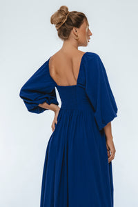 Woman wearing a blue dress with a plain background