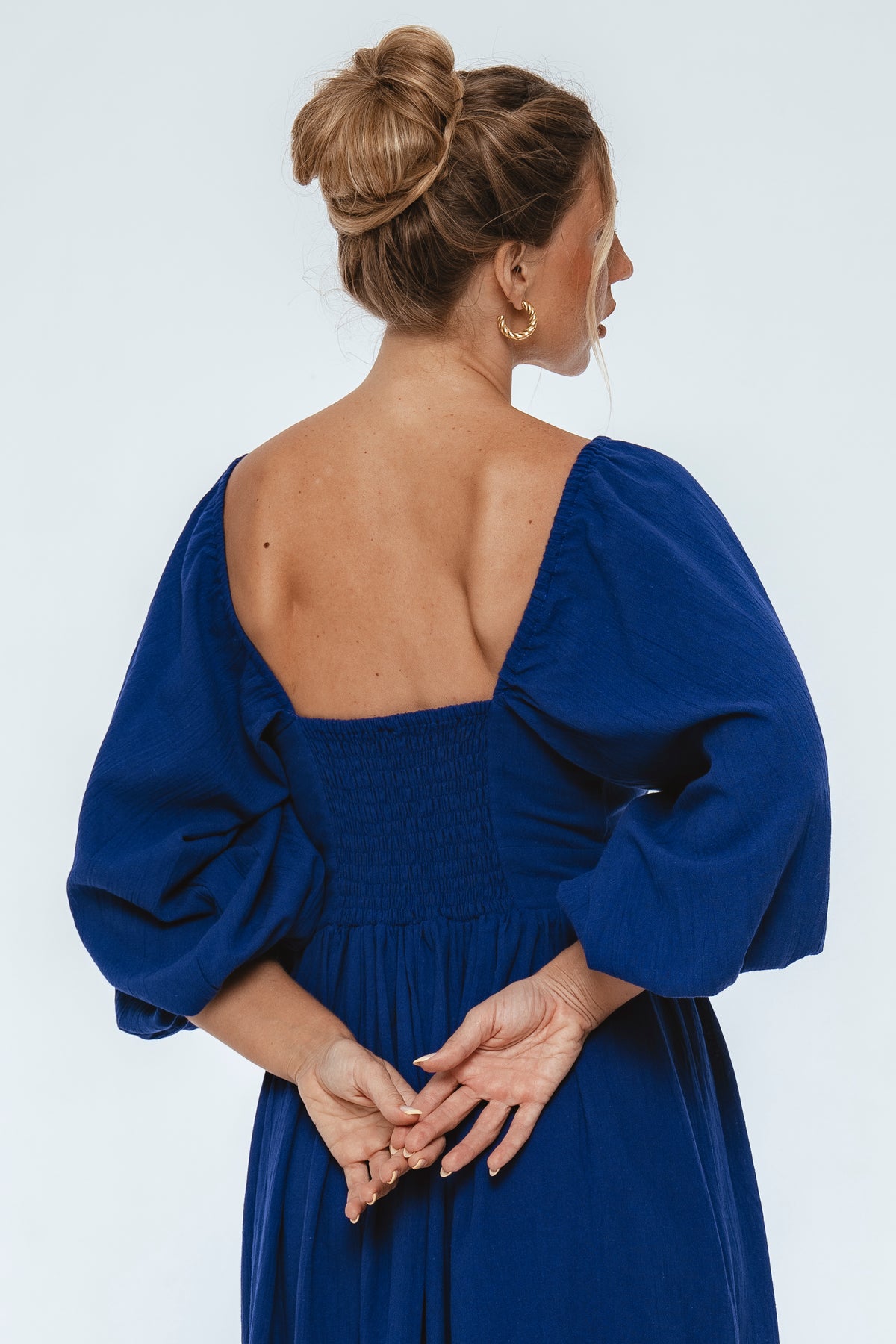 Woman wearing a blue dress with puffed sleeves on a white background
